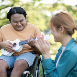 caregiver smiling with her patient while playing guitar